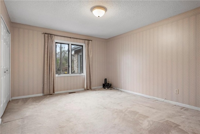 carpeted empty room featuring wallpapered walls, visible vents, baseboards, and a textured ceiling