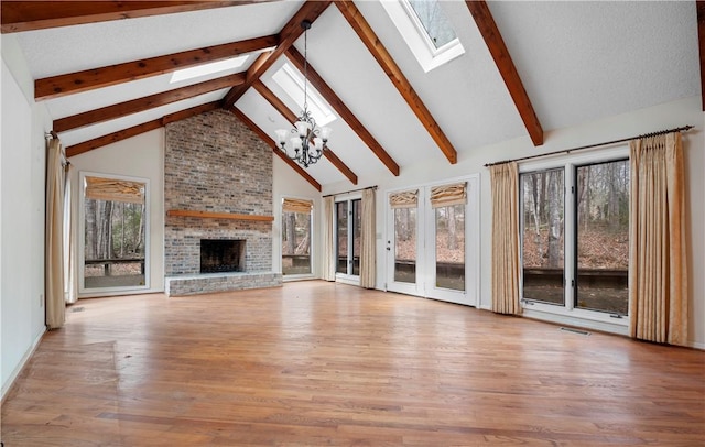 unfurnished living room with a skylight, a fireplace, a chandelier, and wood finished floors