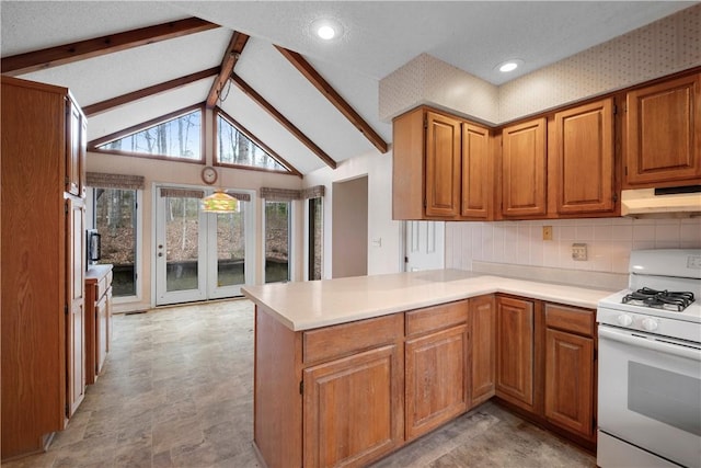 kitchen featuring white gas stove, lofted ceiling with beams, brown cabinetry, a peninsula, and under cabinet range hood