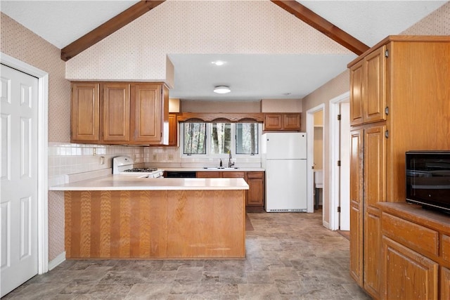 kitchen with wallpapered walls, white appliances, vaulted ceiling with beams, a peninsula, and a sink