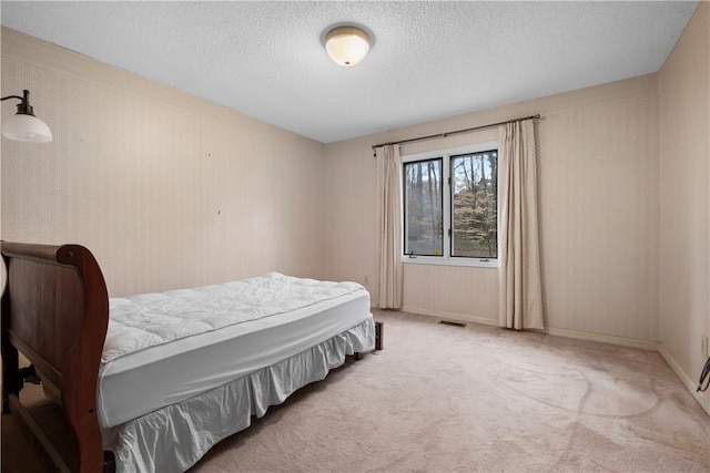 bedroom with a textured ceiling, carpet, visible vents, and baseboards