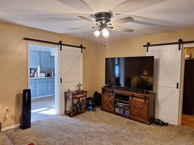 living room with carpet, a barn door, and ceiling fan