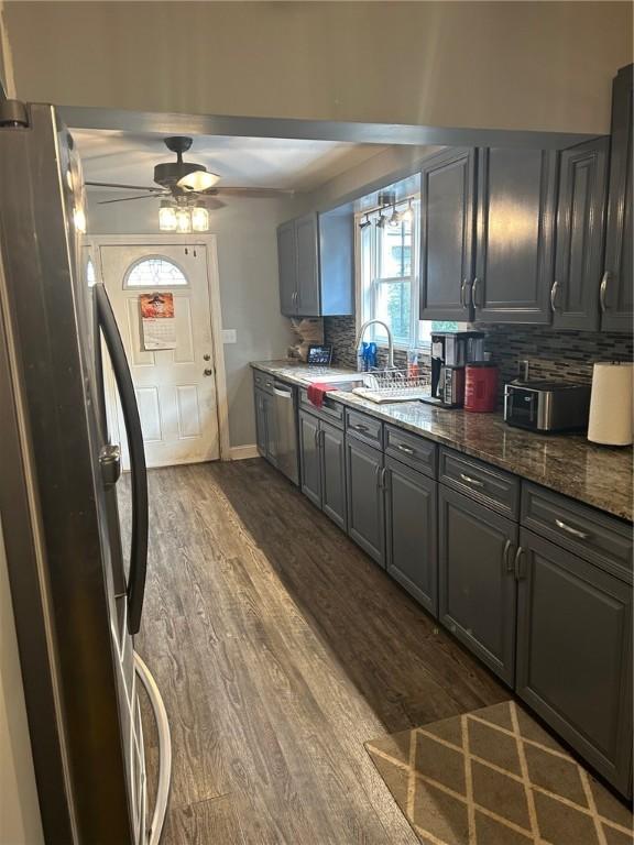 kitchen featuring gray cabinets, dark wood-type flooring, appliances with stainless steel finishes, and tasteful backsplash