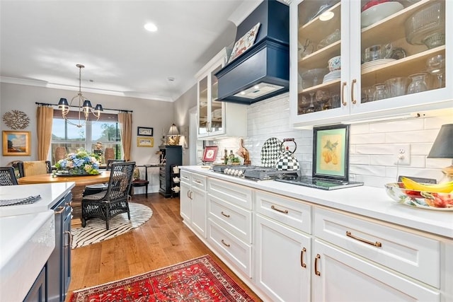 kitchen with backsplash, premium range hood, decorative light fixtures, a notable chandelier, and white cabinets