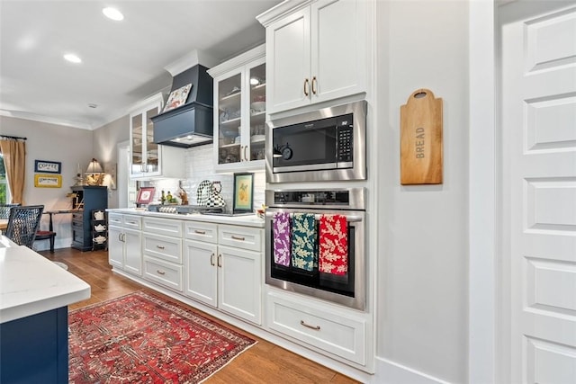 kitchen featuring white cabinets, hardwood / wood-style floors, stainless steel appliances, and decorative backsplash