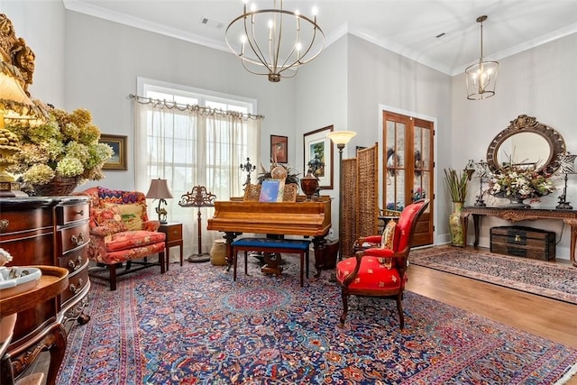 sitting room with wood-type flooring, a notable chandelier, and ornamental molding