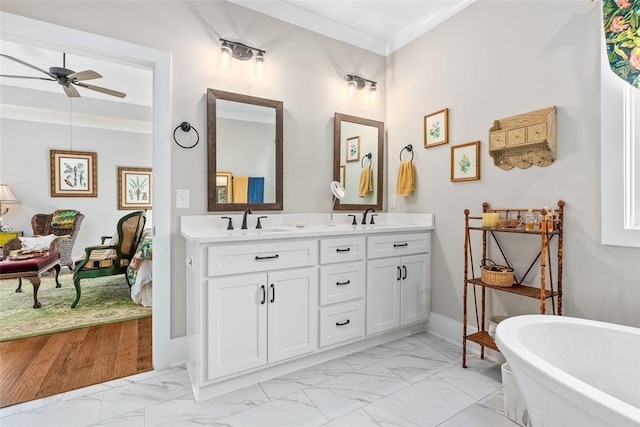 bathroom featuring ceiling fan, crown molding, vanity, and a tub