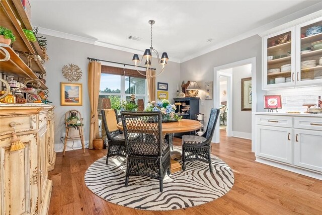 dining space featuring crown molding, light hardwood / wood-style flooring, and a chandelier