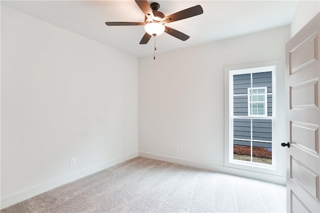 spare room featuring a ceiling fan, light carpet, and baseboards