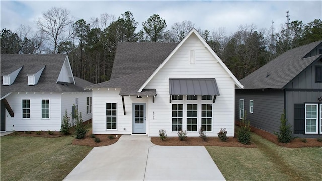 modern farmhouse with a front lawn and roof with shingles