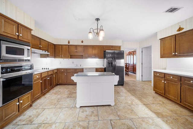 5004 22nd Ave, Phenix City, AL 36867 - kitchen with oven, refrigerator with ice dispenser, stainless steel microwave, a chandelier, and brown cabinets