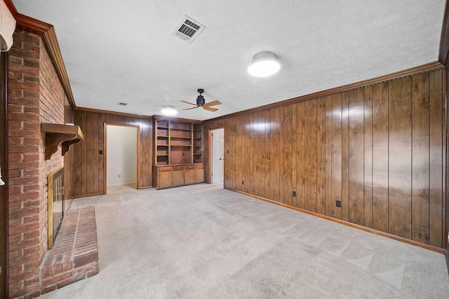 5004 22nd Ave, Phenix City, AL 36867 - unfurnished living room featuring a fireplace, wood walls, ceiling fan, a textured ceiling, and built in shelves