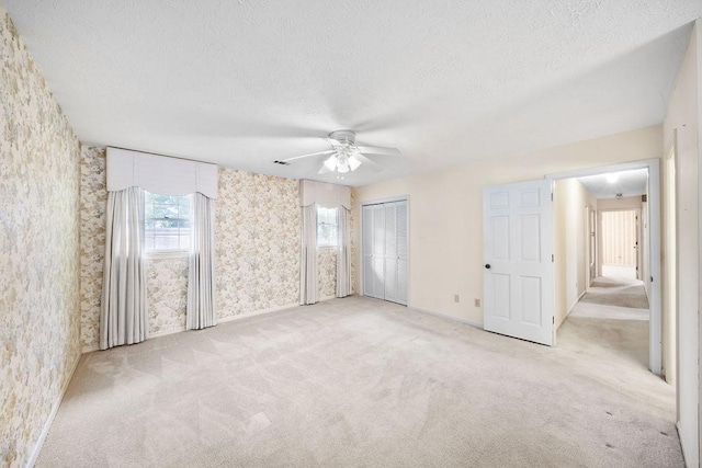 5004 22nd Ave, Phenix City, AL 36867 - unfurnished bedroom featuring wallpapered walls, a textured ceiling, light carpet, and a ceiling fan