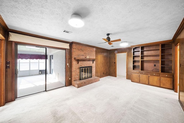 5004 22nd Ave, Phenix City, AL 36867 - unfurnished living room featuring ornamental molding, wood walls, a ceiling fan, a fireplace, and light colored carpet