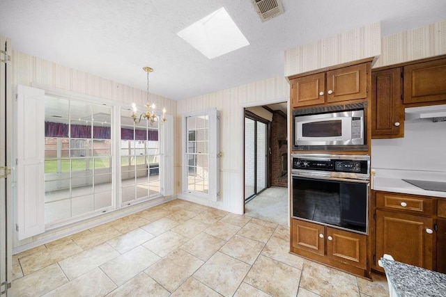 5004 22nd Ave, Phenix City, AL 36867 - kitchen with appliances with stainless steel finishes, a chandelier, a skylight, wallpapered walls, and brown cabinets