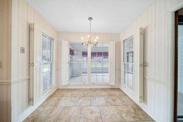 5004 22nd Ave, Phenix City, AL 36867 - unfurnished dining area featuring a chandelier, wallpapered walls, a textured ceiling, light stone finish floors, and plenty of natural light