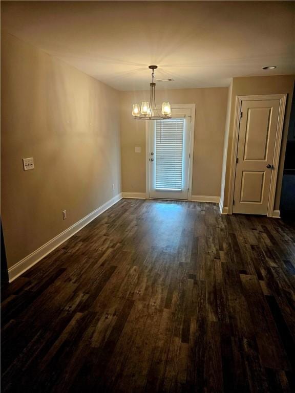 unfurnished dining area featuring an inviting chandelier and dark hardwood / wood-style flooring