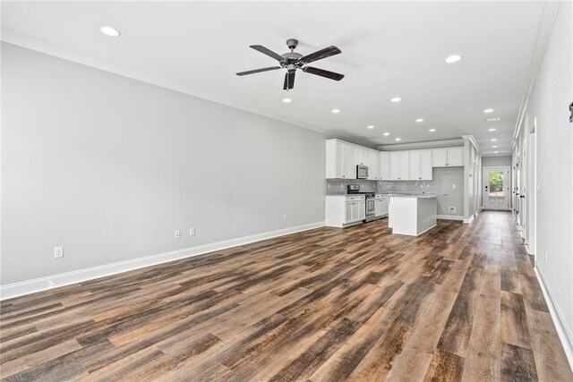 unfurnished living room with dark wood-style floors, crown molding, and baseboards