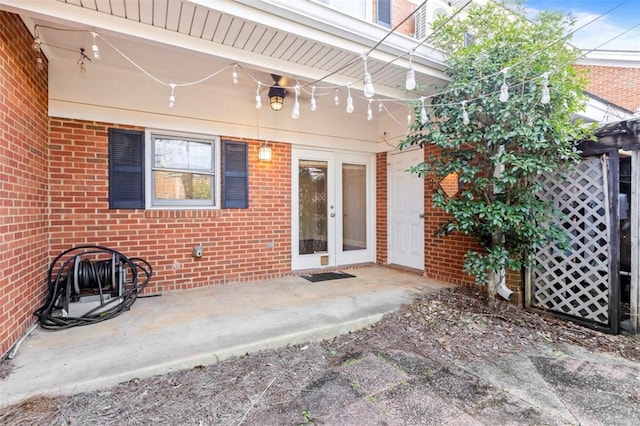 entrance to property featuring french doors, brick siding, and a patio