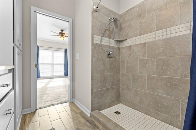 bathroom with a stall shower, baseboards, ceiling fan, wood finished floors, and vanity