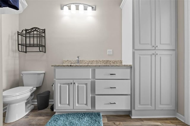 bathroom with toilet, baseboards, wood finished floors, and vanity