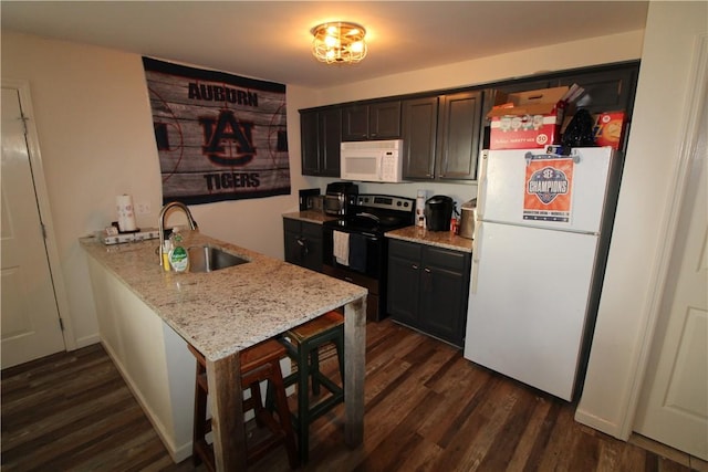 kitchen featuring white appliances, sink, light stone counters, dark hardwood / wood-style flooring, and kitchen peninsula