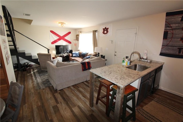 kitchen with dishwasher, dark wood-type flooring, sink, light stone countertops, and kitchen peninsula