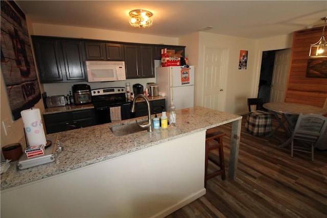 kitchen with light stone countertops, sink, decorative light fixtures, white appliances, and a kitchen bar