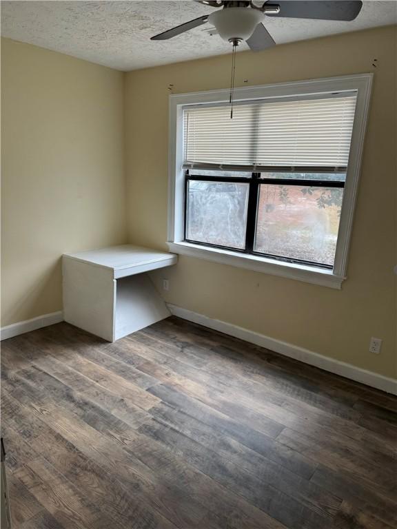 unfurnished room with a textured ceiling, dark hardwood / wood-style flooring, and ceiling fan