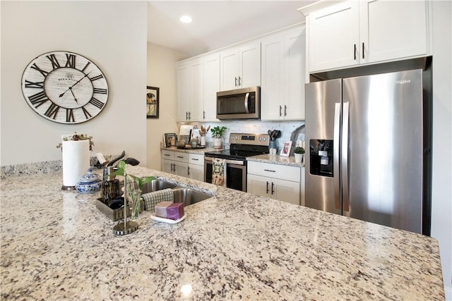 3855 Academy Dr Unit 402, Opelika, AL 36801 - kitchen featuring appliances with stainless steel finishes, light stone counters, decorative backsplash, and white cabinets