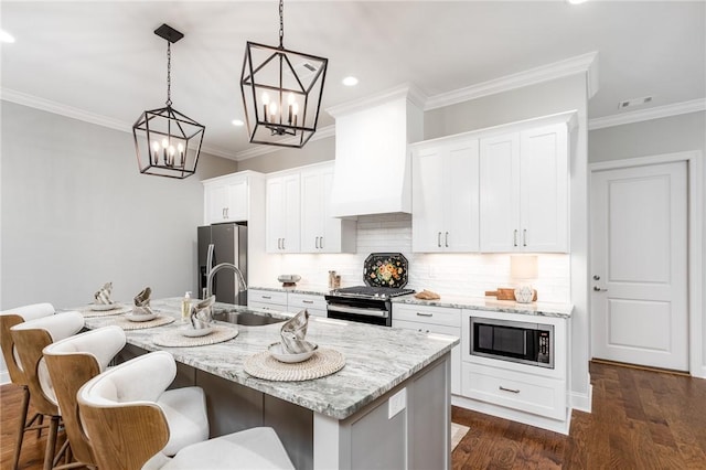 kitchen featuring stainless steel appliances, pendant lighting, a center island with sink, and light stone counters