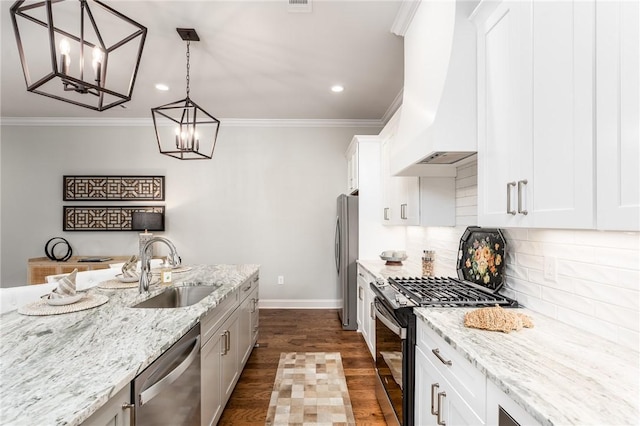 kitchen with sink, custom exhaust hood, white cabinetry, appliances with stainless steel finishes, and pendant lighting