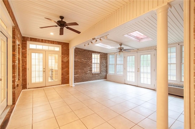 tiled empty room with a wealth of natural light, french doors, and brick wall