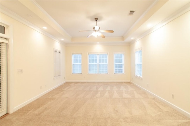 carpeted spare room with ceiling fan, a raised ceiling, and ornamental molding