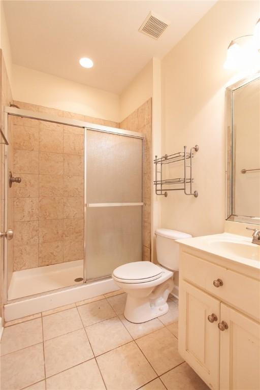 bathroom featuring tile patterned flooring, vanity, an enclosed shower, and toilet