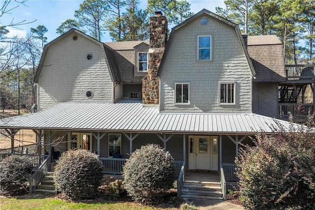 view of front of property featuring roof with shingles, a chimney, a porch, and a gambrel roof