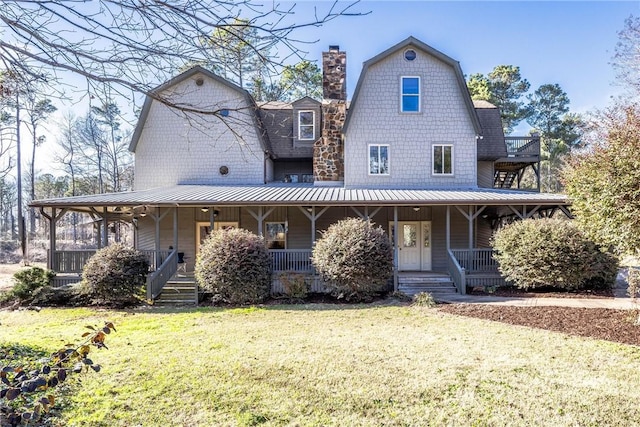 back of property with a chimney, a porch, a lawn, and a gambrel roof