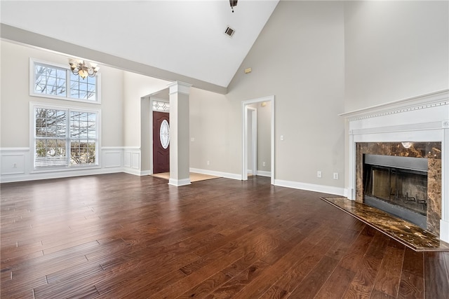 unfurnished living room with ornate columns, a premium fireplace, dark wood-type flooring, and high vaulted ceiling