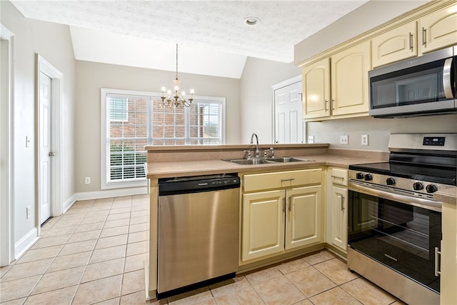 kitchen with lofted ceiling, sink, kitchen peninsula, stainless steel appliances, and cream cabinetry