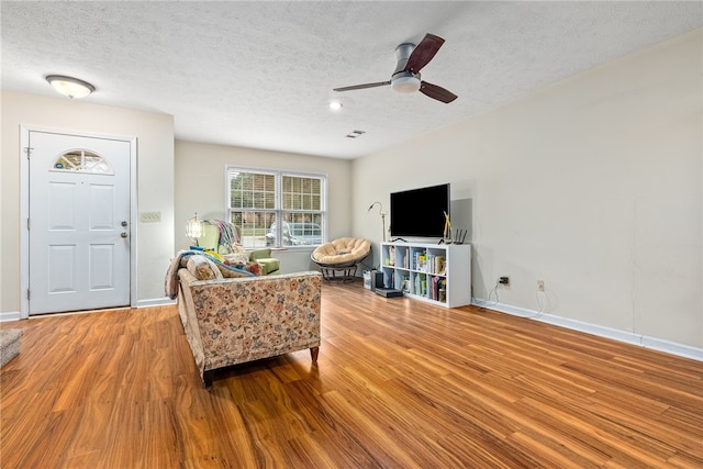 living room with ceiling fan, a textured ceiling, and hardwood / wood-style flooring