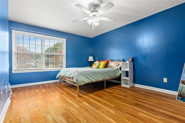 bedroom featuring ceiling fan, wood-type flooring, and a textured ceiling