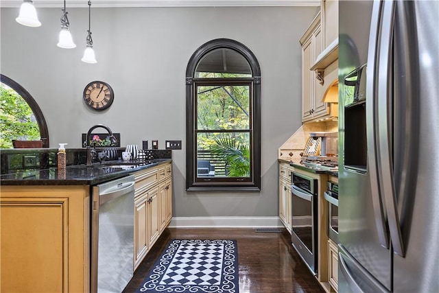 kitchen featuring sink, hanging light fixtures, dark hardwood / wood-style floors, dark stone countertops, and appliances with stainless steel finishes