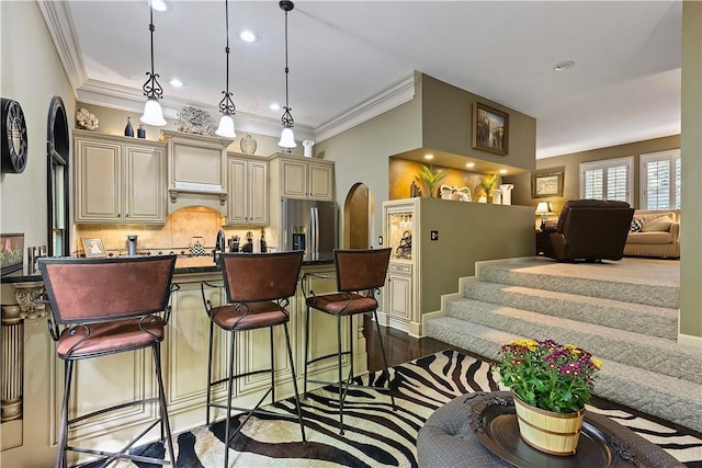 kitchen featuring stainless steel refrigerator with ice dispenser, tasteful backsplash, cream cabinetry, dark hardwood / wood-style floors, and hanging light fixtures