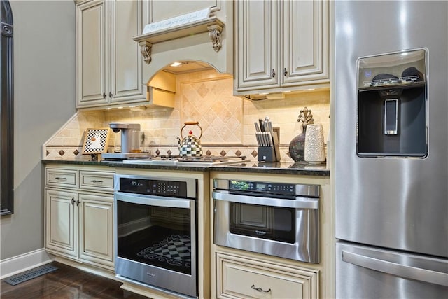 kitchen with backsplash, custom exhaust hood, stainless steel appliances, and cream cabinetry