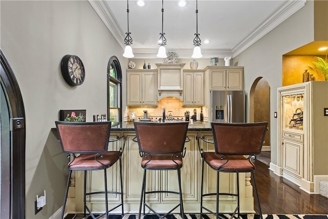 kitchen with cream cabinetry, stainless steel fridge with ice dispenser, pendant lighting, and a kitchen breakfast bar