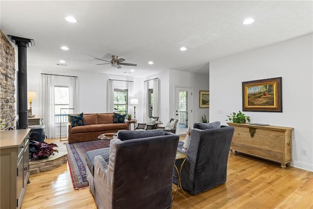 living area featuring a wood stove, light wood-style flooring, a ceiling fan, and recessed lighting