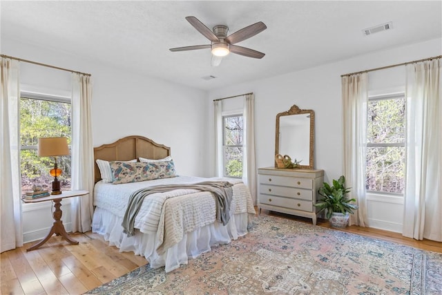 bedroom featuring baseboards, ceiling fan, visible vents, and wood finished floors