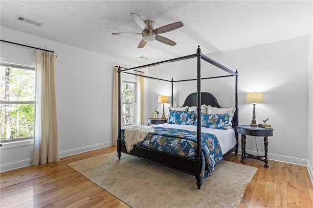 bedroom featuring multiple windows, hardwood / wood-style floors, and visible vents
