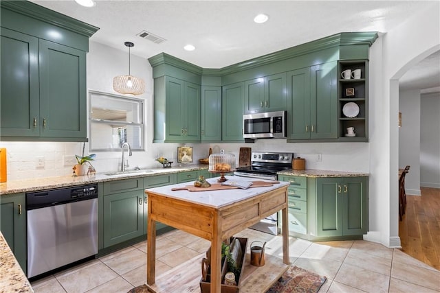 kitchen with a sink, stainless steel appliances, visible vents, green cabinets, and arched walkways