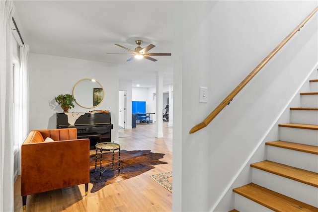 staircase with wood finished floors and a ceiling fan